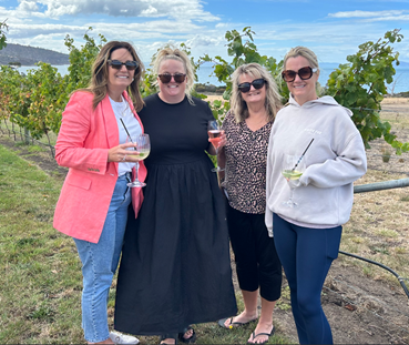 Four women post in a winery