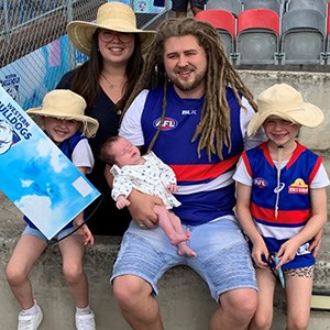 Aaron with his family at the football. They are all smiling.