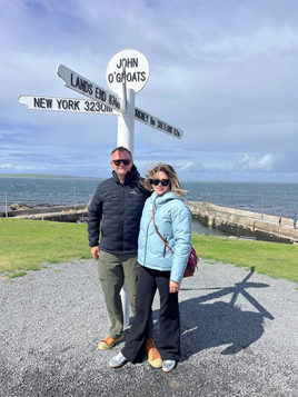 A man and woman stand in front of a street sign