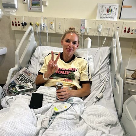 Brooke in her hospital bed giving a victory sign