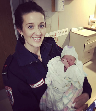 Bec as a paramedic holding a baby she had just delivered